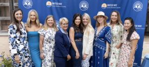 women standing in front of step and repeat